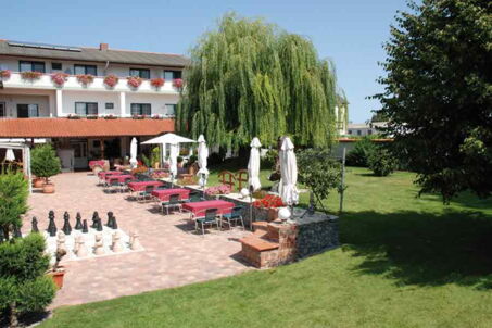 Gartenansicht mit Blick auf Haus, Balkone, Wiese, Schachspiel und Sitzmöglichkeiten