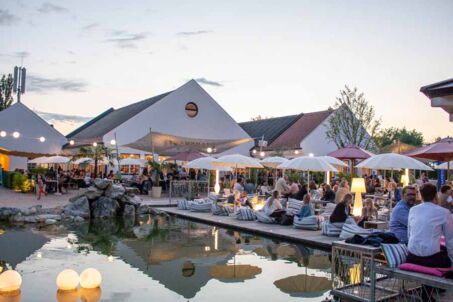 Strandhaus Überblick, Teich, Sitzmöglichkeiten, Sonnenschirme, viele Leute