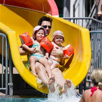 Wasserrutsche mit Mann und zwei Kindern mit Schwimmflügerl