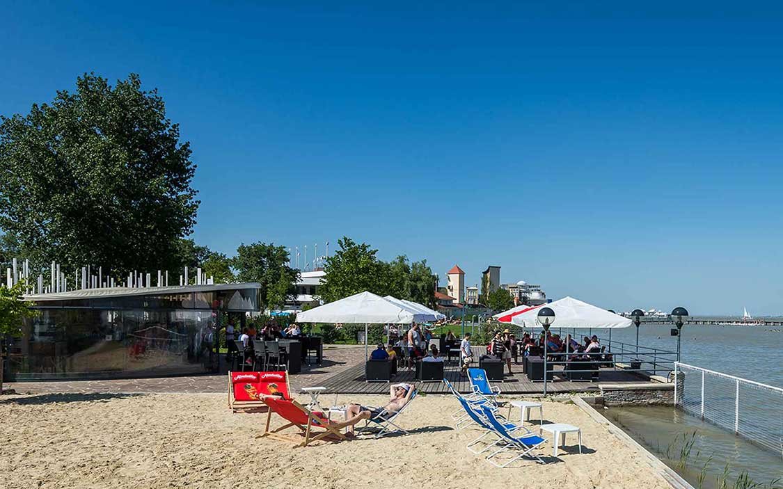 Seeterrasse mit Sonnenschirmen und Sandplatz mit Liegestühlen in Mörbisch am See