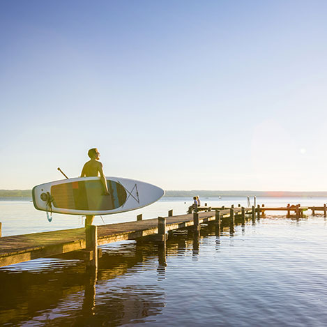 Mann geht mit Stand Up Paddle auf Steg